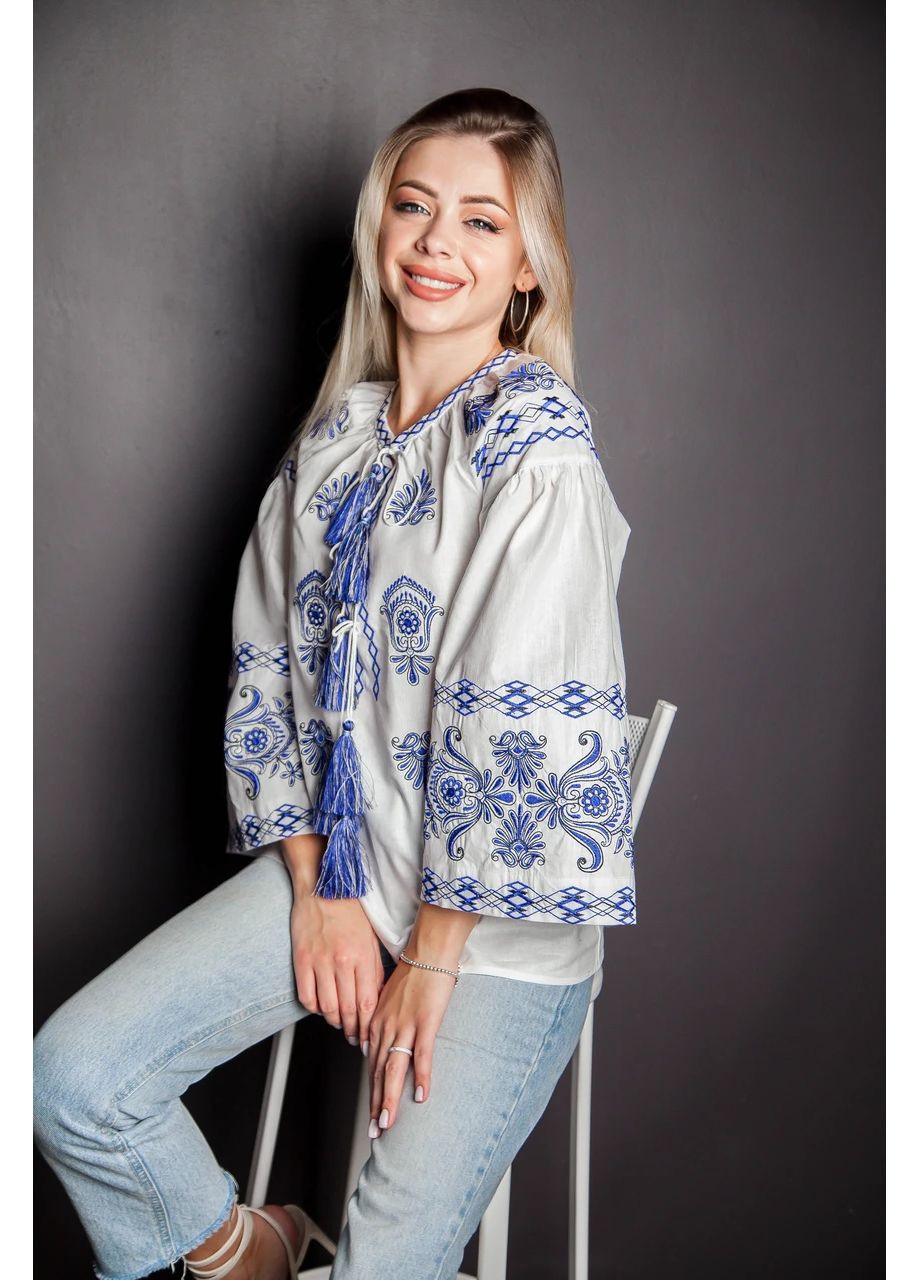 Біла жіноча вишиванка з синьою гладдю на молочній бавовняній бязі з широкими рукавами та етнічними китицями, s бязь (301033782)
