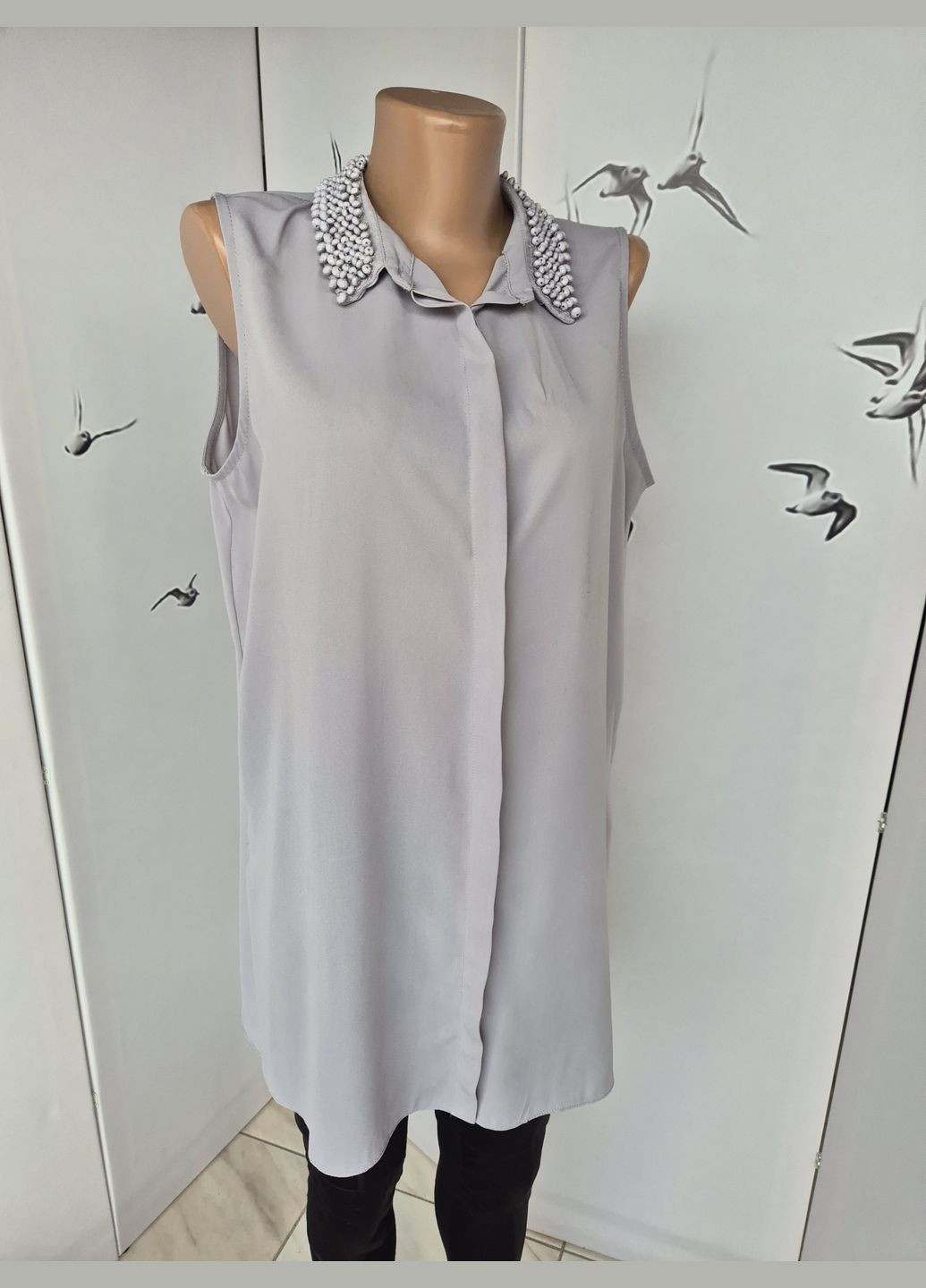 Сіра подовжена жіноча блузка без рукавів однотонна з намистинками на комірі Wallis