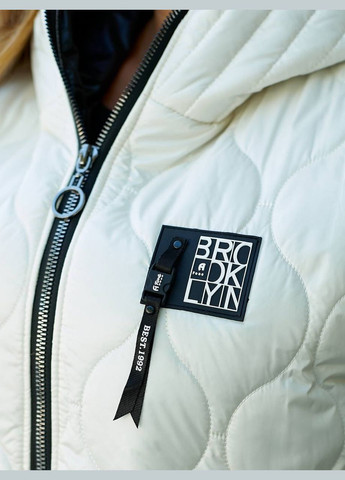 Женская демисезонная объемная жилетка молочного цвета батал стеганая длинная до колена с капюшоном на молнии Viki Жилет (316093991)